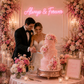 Bride and Groom cutting an elegant pink wedding cake in front of a neon sign that says always & forever