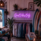 Neon sign reading 'Good Vibes Only' in a store with clothing racks and surfboards.