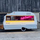 Food truck with a neon sign on a wooden building background