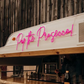 Neon sign on a food truck with 'Pop the Prosecco!' text, wooden interior.