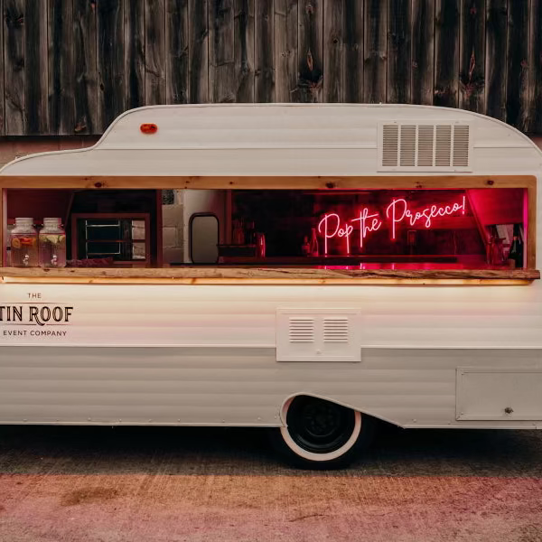 White trailer with a neon sign and 'Tin Roof' branding against a rustic wooden wall.