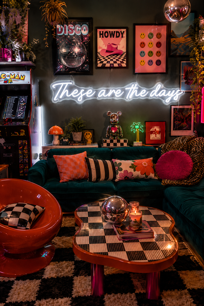 Neon sign that says 'these are the days'  in a retro-themed, maximalist living room with decor elements.