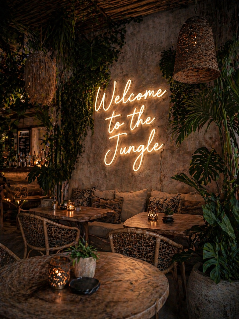 Neon sign 'Welcome to the Jungle' in a cozy, dimly lit outdoor seating area with plants and tables.
