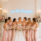 Bridesmaids in pink dresses with the bride holding flowers in a elegant room.