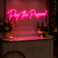 Decorative bar setup with 'Pop the Prosecco!' neon sign, champagne bottles, and glasses.